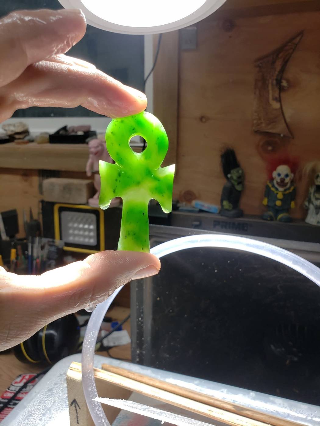 Translucent green jade ankh pendant held up to the light